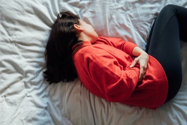 woman has stomachache , lying on the bed