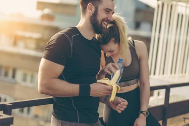 Couple resting after a workout having a banana and water, which is a good Gatorade alternative