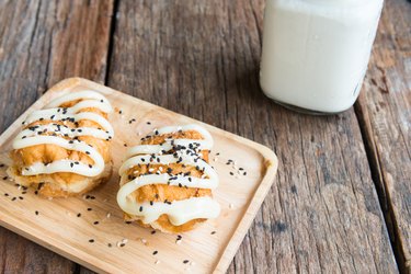 Buns with Sweetened Condensed Milk and Sesame black and white , with glass of milk on wooden background