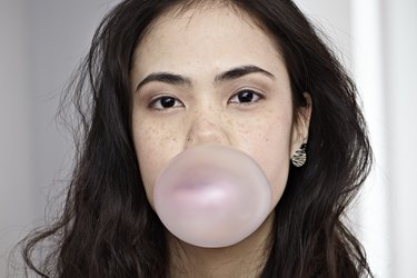 Germany, Cologne, Young woman blowing bubble gum