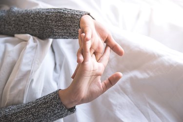 Cropped Image Of Woman Stretching Hands While Lying On Bed At Home
