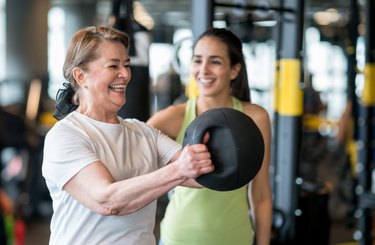 Adult woman exercising at the gym with a personal trainer