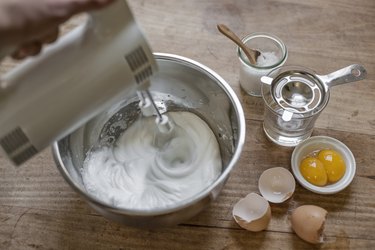 Beating egg white with electric whisk, elevated view