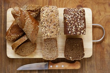 Low-carb bread options made with whole-grain ingredients such as oat and rye on a cutting board on wooden table
