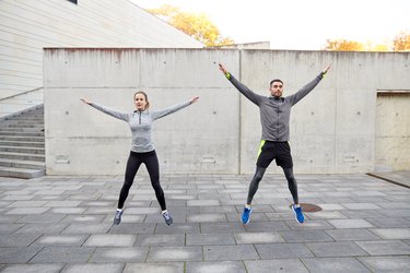 happy man and woman jumping outdoors