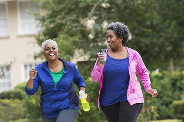 Two older adults over 50 exercising together outside
