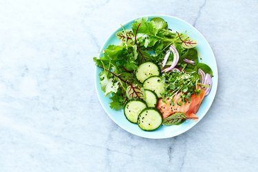 Mixed leaf salad with smoked salmon, cucumber, red onion, herbs and black kumin. Healthy diet. Low carb meal. Flat lay. Copy space