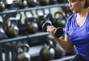 Hispanic woman at gym lifting dumbbell