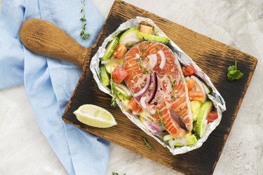 Raw salmon steak with vegetables in a foil boat