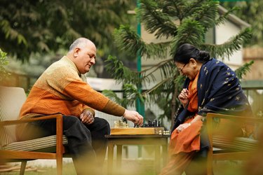 couple seated in garden playing chess