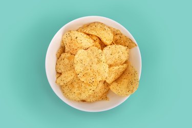 Close-up of potato chips in a bowl on turquoise background to avoid before colonoscopy procedure