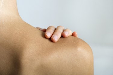 Woman with hand on bare shoulder, close-up