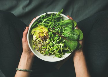 Meal with magnesium-rich spinach, arugula, avocado, seeds and sprouts in bowl