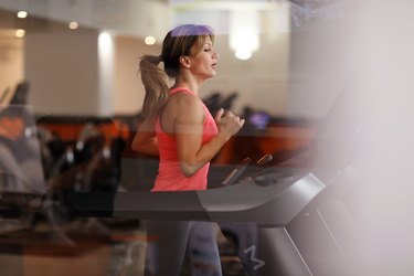 A fit woman running on a treadmill at a fitness center