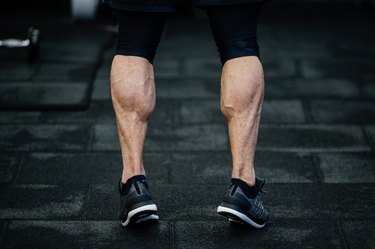 trained legs with muscular calves in sneakers in training gym during hard fitness and gym workout