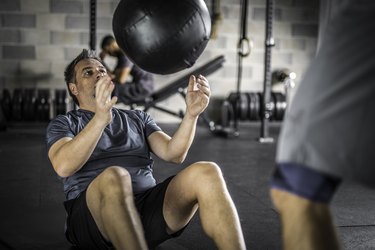 Man doing ab exercises with a medicine ball