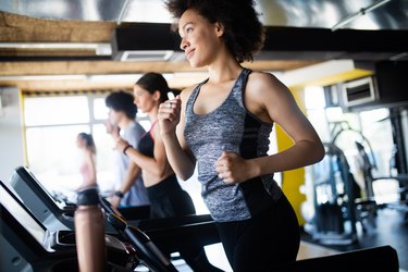 Group of young people running on treadmills in modern sport gym