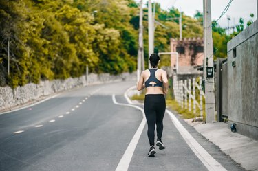 女子跑步者在公园户外锻炼前伸展双腿。健康的概念