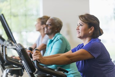 Multiracial women riding exercise bikes at gym