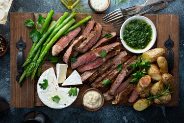 Sliced steak with asparagus and potatoes on wooden board