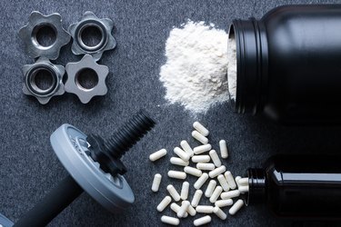 dumbbells, protein and amino acids on a gray background
