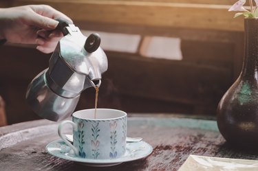 Cropped Hand Of Woman Pouring Tea In Cup