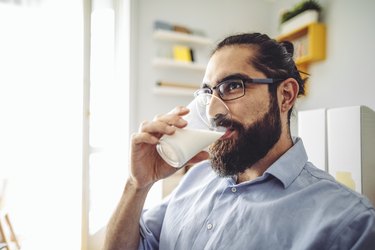 Man drinking glass of milk at home