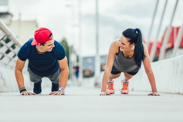 Happy couple doing push-ups outdoors on the bridge