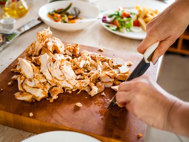 Woman cutting lean chicken breast.