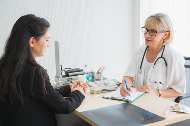 Senior female doctor meet the patient discussing and making notes about symptom problem. Health care and client service in medicine concept.