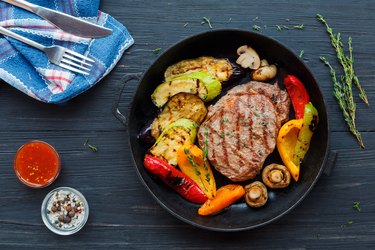 Grilled beef steak on dark wooden table background, top view