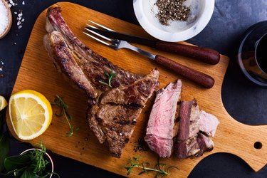 bone-in ribeye steak on cutting board ready to eat, top view