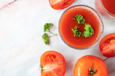 Glass of tomato juice and fresh tomatoes on marble table background. copy space