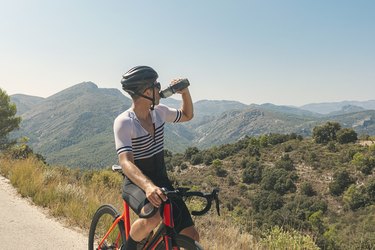 Cyclist drinking from water bottle at summit during summer workout