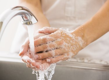A caucasian woman washing her hands with soap and water