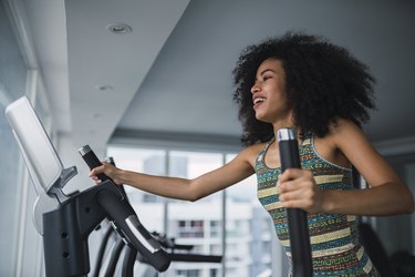 Smiling young woman on stairmaster machine in gym