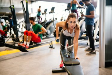 Young woman doing dumbbell exercises at gym