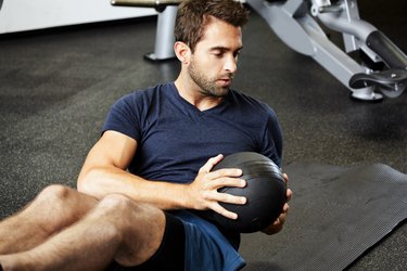 Man using medicine ball to do Russian twist exercise