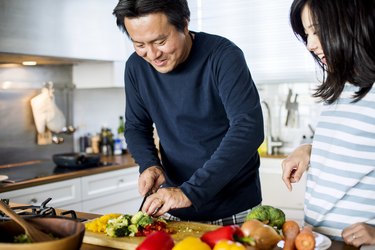 一对亚洲夫妇在厨房做饭，想知道需要多长时间才能变得健康，看看一周干净饮食的结果raybet投注