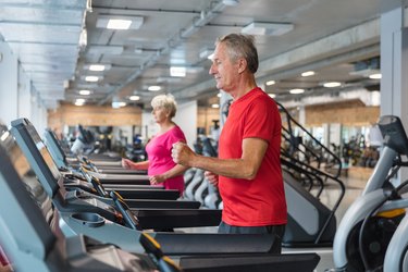 older adults doing treadmill walking workouts at a gym