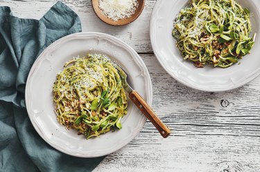 overhead view of spaghetti with avocado, vegetables, spinach and parmesan