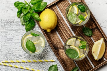 Summer basil lemonade on grey background. Fresh summer cocktail with basil, lemon and ice cubes. Homemade fresh lemonade with lemon and basil. Food and drink concept