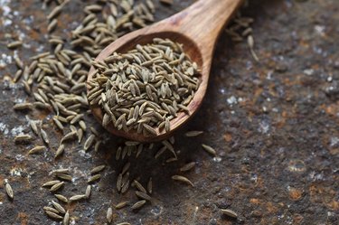 Close view of a wooden spoon full of cumin seeds as a spice for weight loss