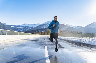 man running on a road in winter with exposed skin