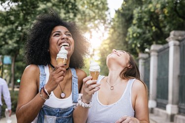 Two young women laughing and eating ice cream in the street