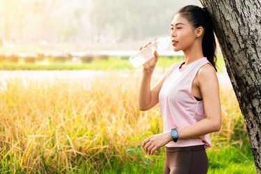 The beautiful women running and exercising beneath a clear sky. She is wearing sport dress in the distance below aresome light and the sun is setting giving a nice warm light.