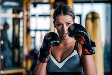 Close-up of a young fit woman in boxing gloves, front view.