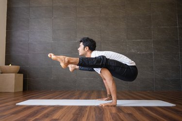 Yogi doing firefly yoga pose at home