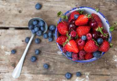 Top view of a variety of berries in a bowl on a wooden background