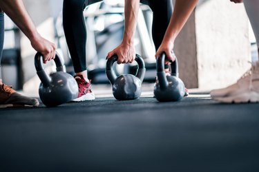 Lifting weights, low angle image. Athletes with kettle bells, close-up.
